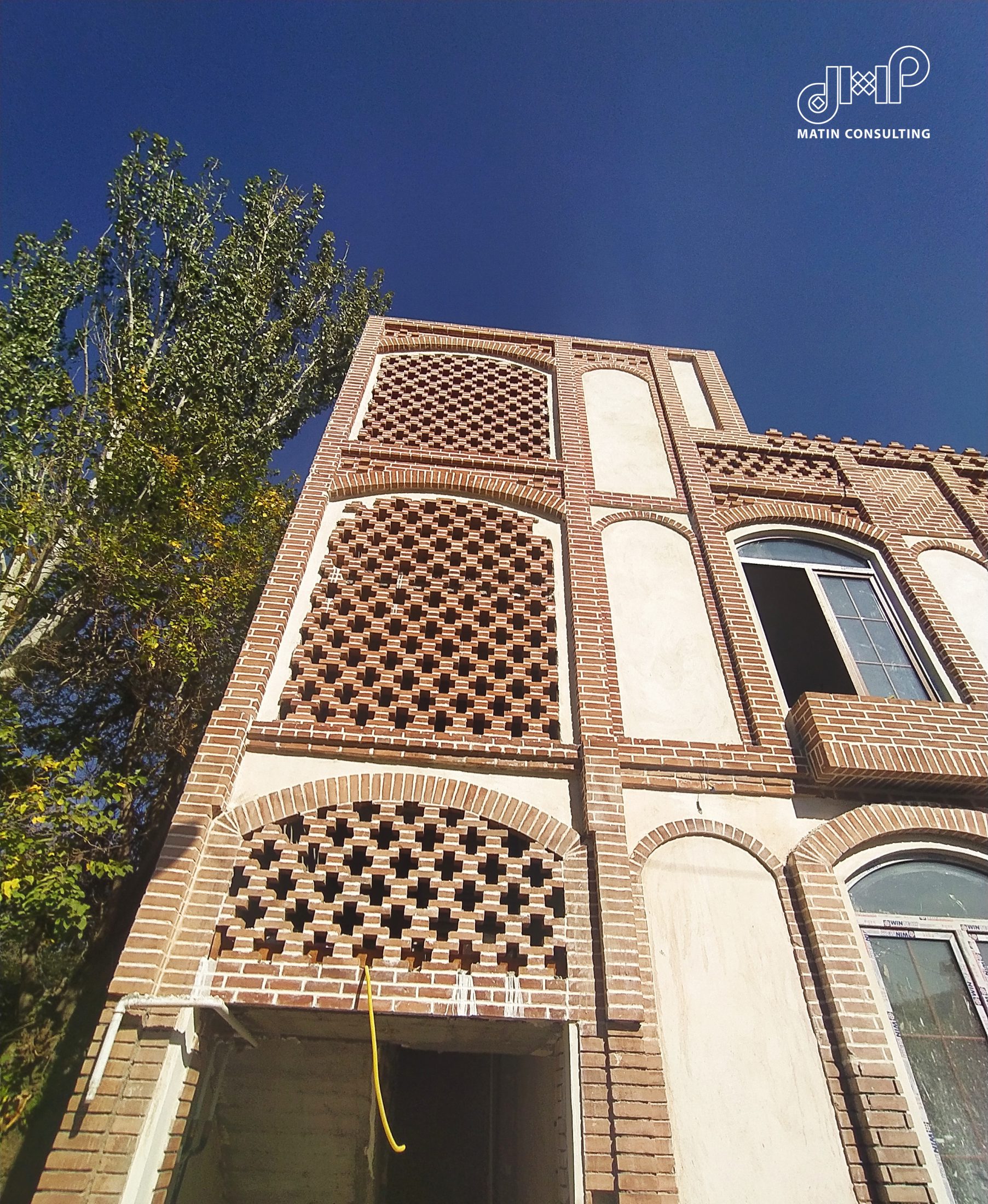 نمای اصلی عمارت ربیعی با قاب‌های مشبک بزرگ و دهانه ورودی در حال اجرا